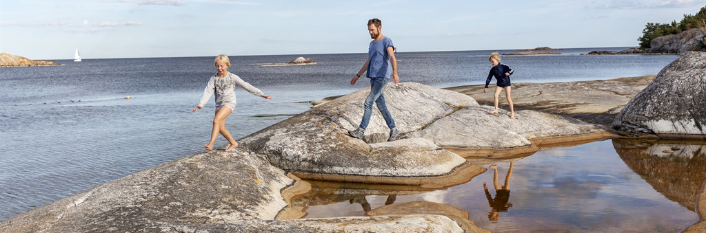 Pappa och barn som går på klippa vid havet