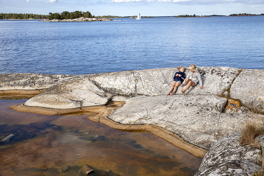 Två barn som ligger på klippa och pratar