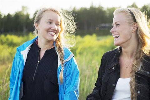 Två tjejer som tittar på varandra och ser glada ut