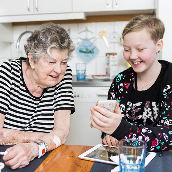 en äldre och en yngre person med en telefon