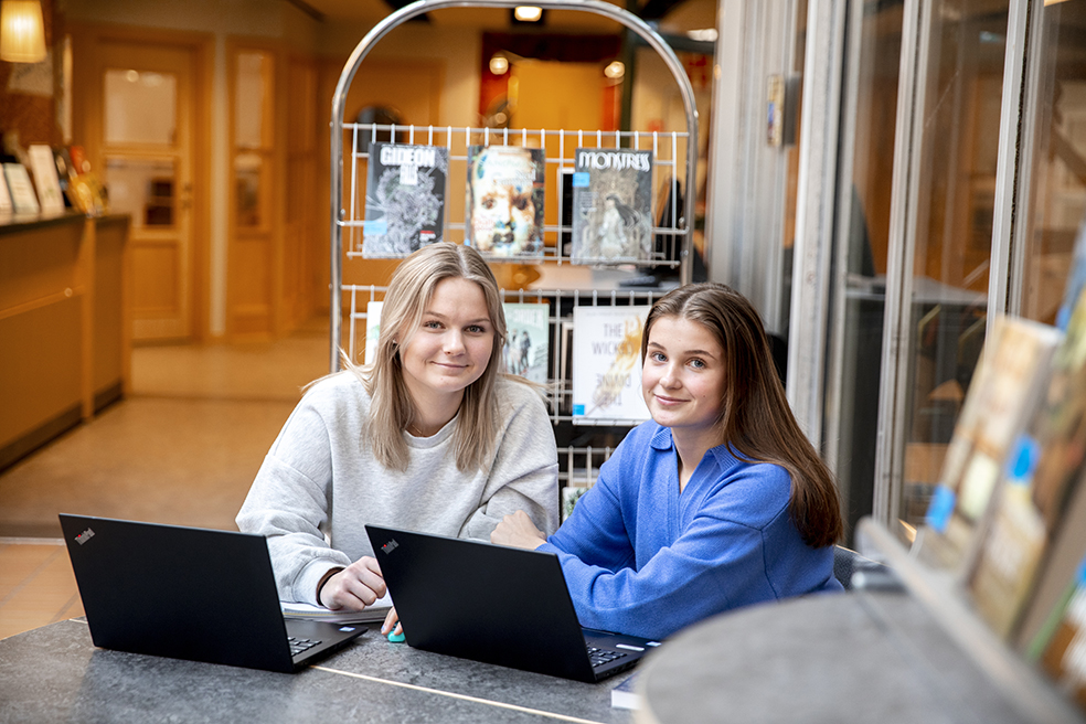 Två flickor i gymnasiebiblioteket